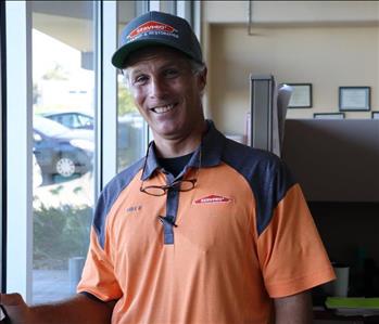 Man in orange shirt standing in office.