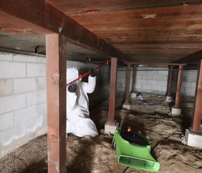 Employee under crawl space setting machine up.