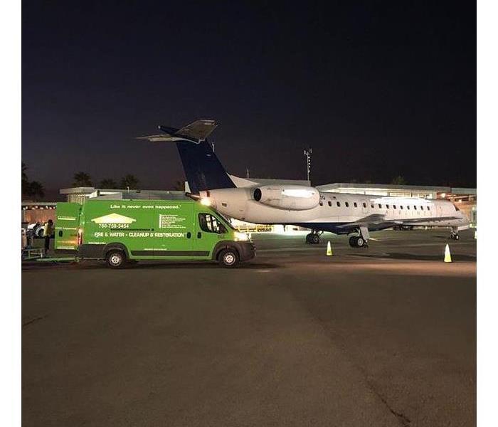 Green truck parked in front of aircraft.