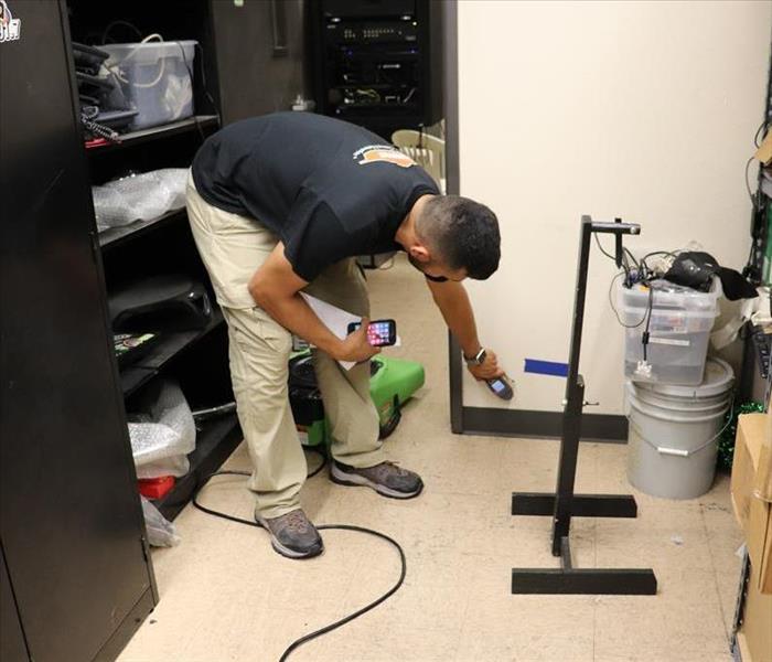 Man checking moisture in wall with device.